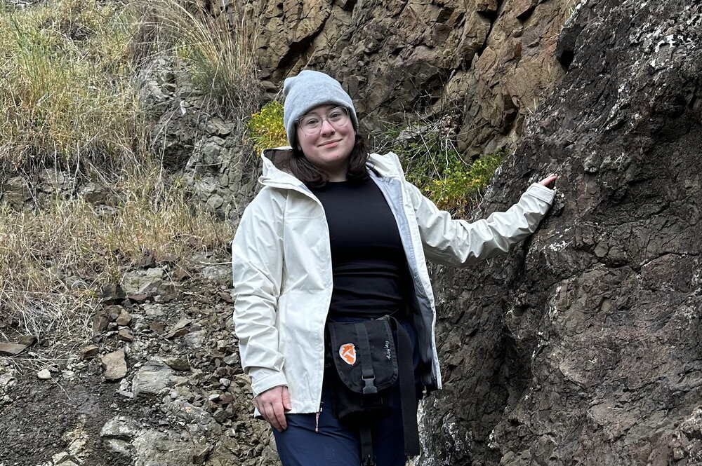 A person standing next to a rocky cliff.