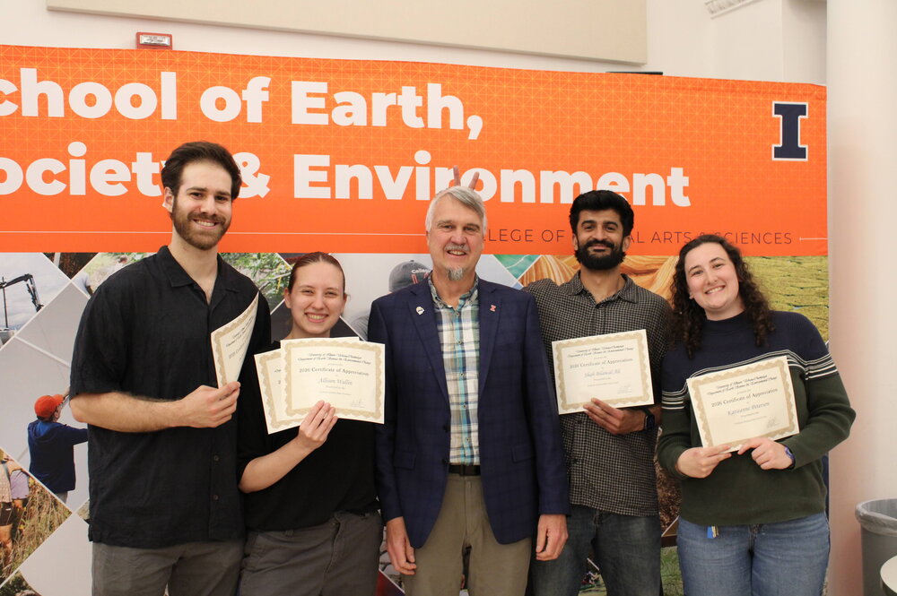 People posing for a photo with award certificates.