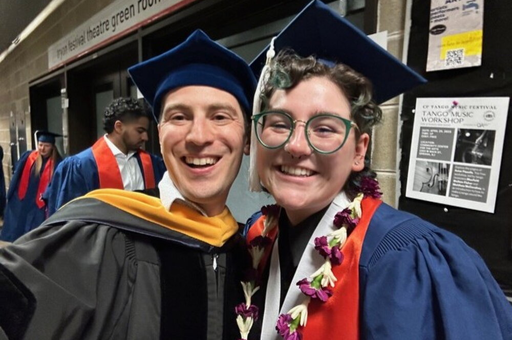 Two people in graduation caps and gowns posing for a picture.