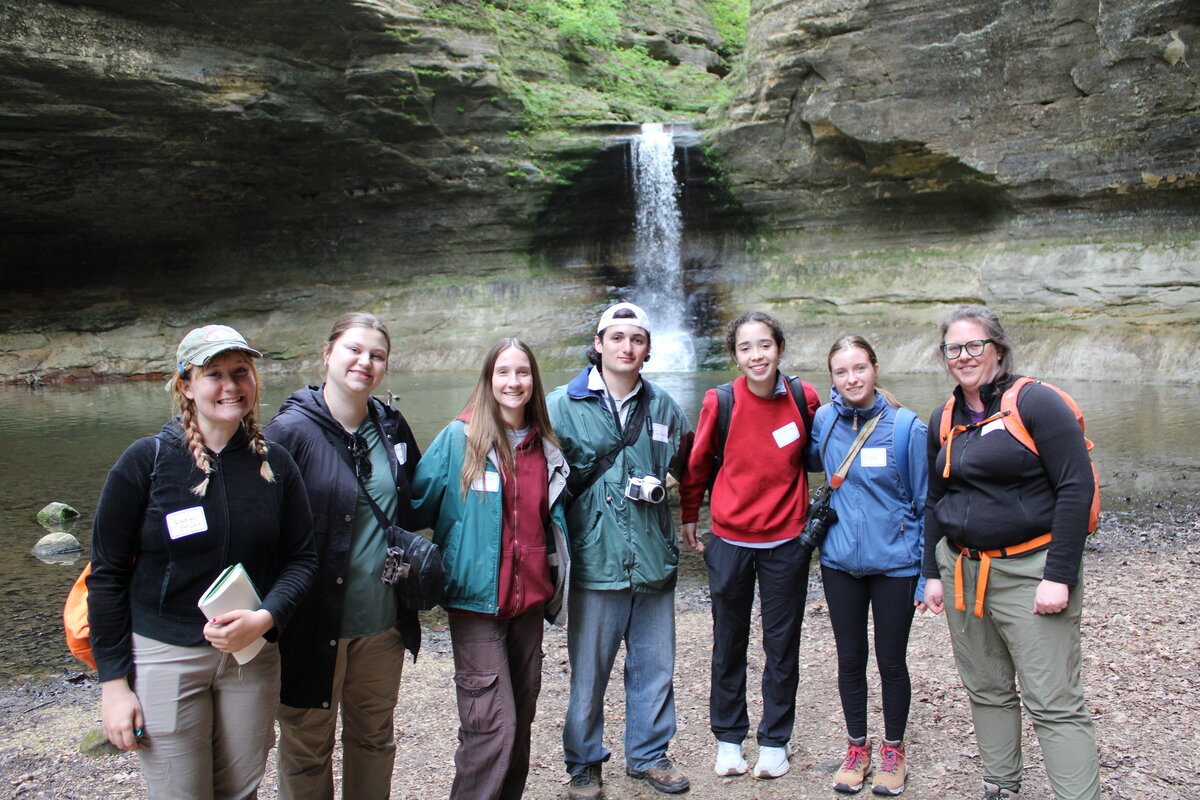 Students dressed for a hike posing for a picture with their professor.