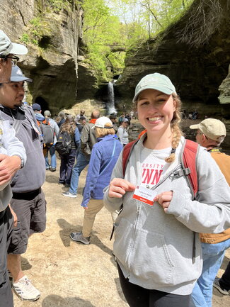 A woman posing for a picture hodling the straps of the backpack