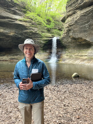 A woman poses for a picture in front of a waterfall