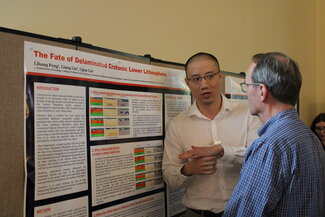 A person talks to a man while presenting his poster