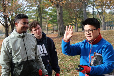 A teacher demonstrating an acorn to a pair of students.