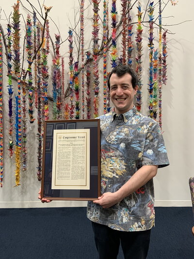 A man holding a framed senate resolution.