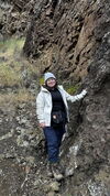 A person standing next to a rocky cliff.