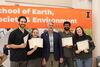 People posing for a photo with award certificates.