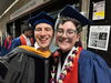 Two people in graduation caps and gowns posing for a picture.